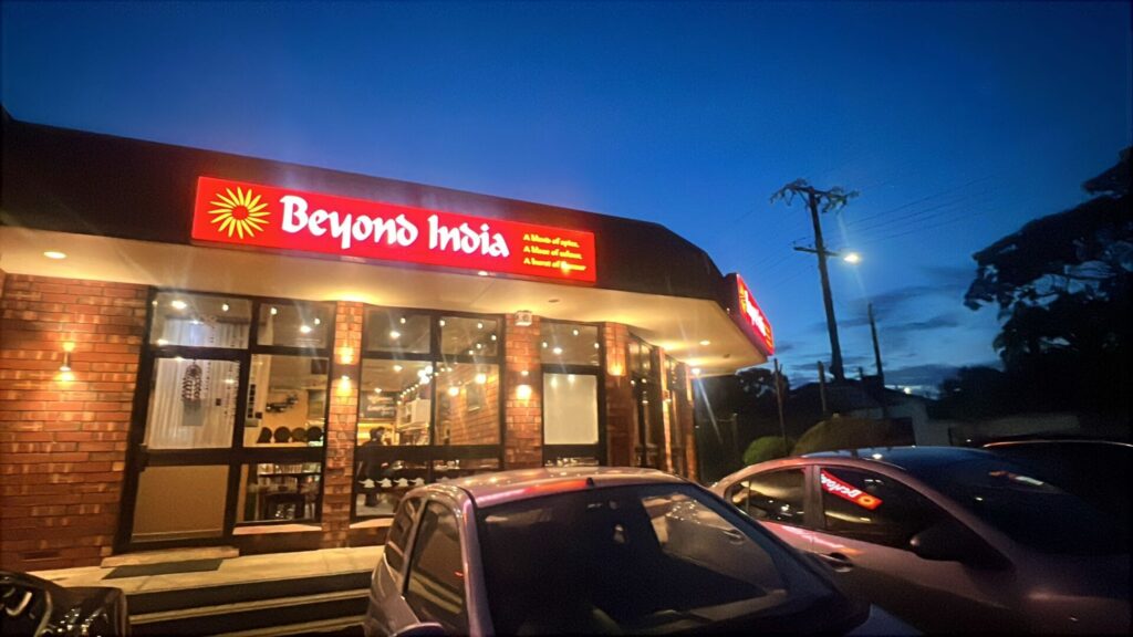 Beyond India Adelaide restaurant exterior at night with illuminated signage and warm dining room visible through windows